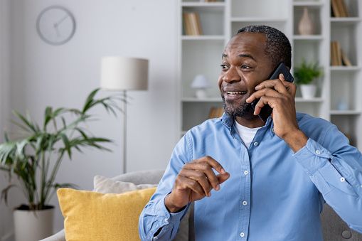 Happy man talking on the phone while sitting at home on the sofa